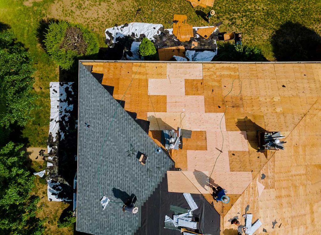 A close-up view of a house roof showing both asphalt shingles and metal panels side by side.