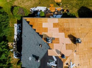A close-up view of a house roof showing both asphalt shingles and metal panels side by side.